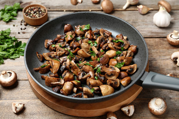 Frying pan with mushrooms on wooden table