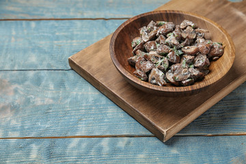 Bowl of fried mushrooms with sauce on wooden table. Space for text
