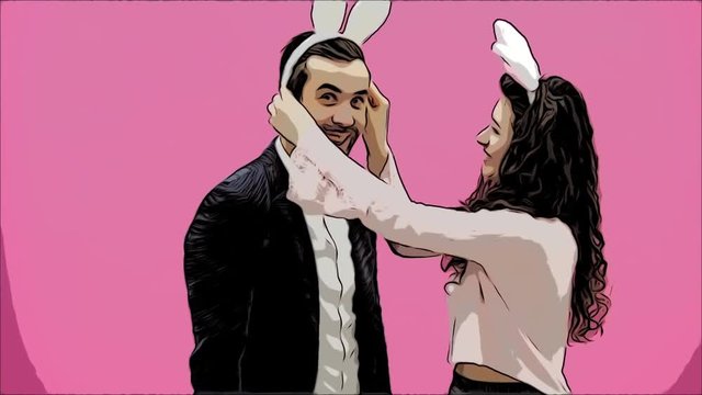Young lovers couple on the pink background. With hackneyed ears on the head. During this, the girl wears rabbit ears to her husband. After that, they begin to make a photo of sephi on the phone. Very