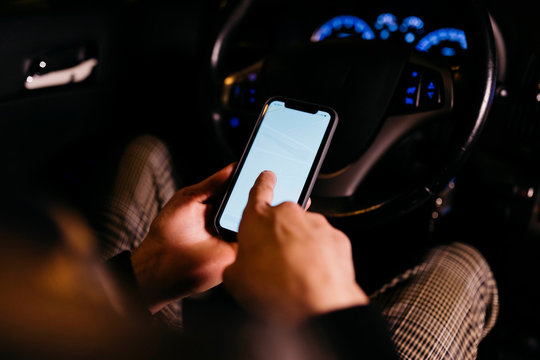 Man using cell phone in the car at night