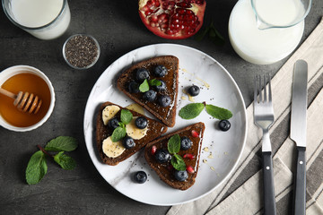 Fototapeta na wymiar Different toasts with fruits, blueberries, honey and chia seeds served on table, top view