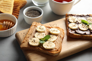 Tasty toasts with banana, mint and chia seeds on wooden board