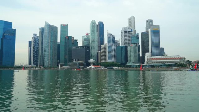 Time-Lapse boat traffic moves in and out of Singapore low wide angle from water level to the city center.