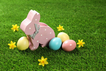Fototapeta na wymiar Cute wooden Easter bunny and dyed eggs on green grass