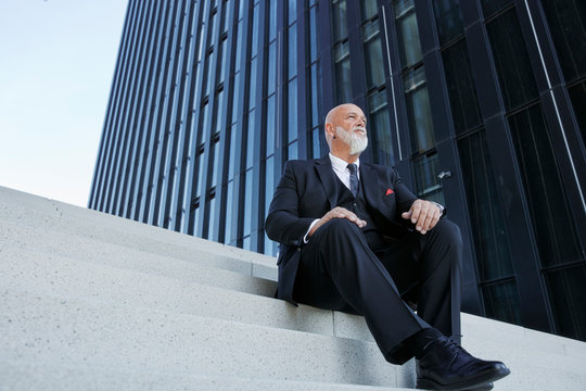 Elegant businessman, sitting on stairs in the city