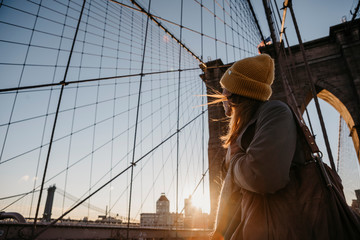 USA, New York, New York City, female tourist on Brooklyn Bridge at sunrise