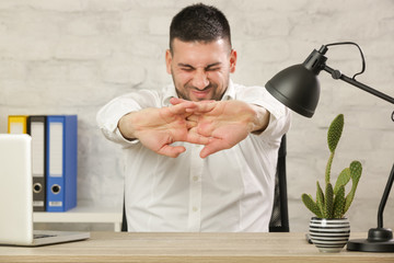 Businessman sitting at the office desk and stretching his arms.