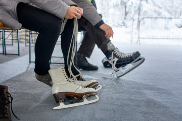 Couple sitting on bench at the ice rink, putting on ice skates