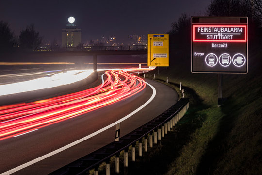 Germany, Stuttgart, Warning sign for particulate pollution alert and traffic at night