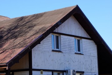 facade of a gray wooden house under a brown slate on the roof