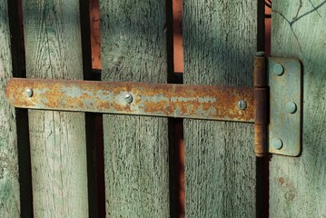 rusty hinge on green wooden fence boards