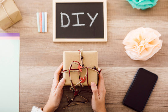 Top view of young woman showing a wrapped gift in her studio