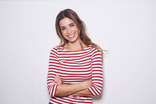 Portrait of laughing young woman wearing red-white striped shirt against white background