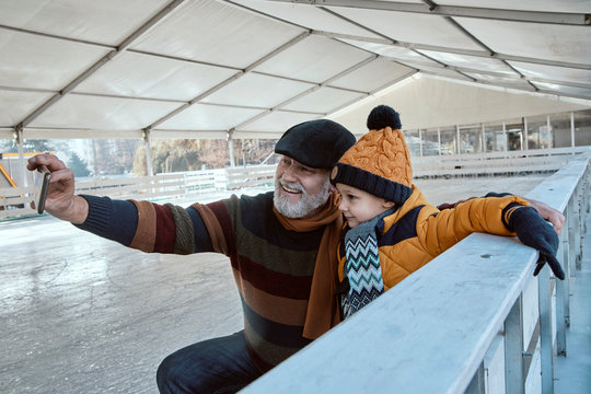 Grandfather and grandson on the ice rink, taking selfies