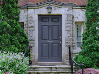 front door of stone faced house surrounded by cedar bushes