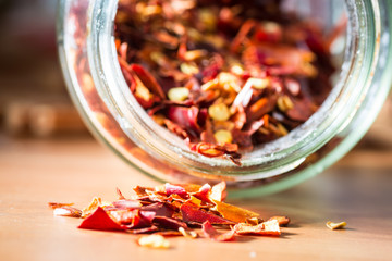 Dried red chili pepper flakes in a bottle jar. close up. 