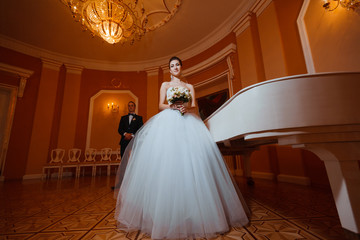 Newlyweds near the piano.In love with the luxurious interior.Wedding photo