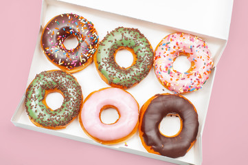 Colorful donuts in box on pink background