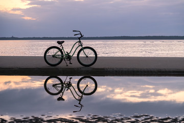Fototapeta na wymiar Silhouetted Bicycle at Sunset, East Beach, St Simons Island, GA
