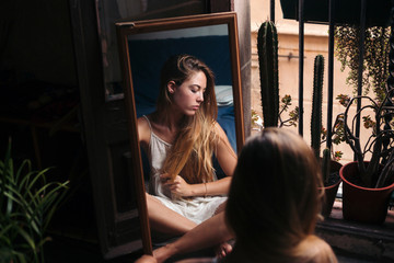 Mirror image of young woman sitting on the floor at home relaxing