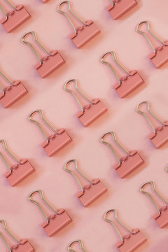 Pink paper clips against pink background