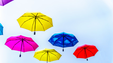 Fototapeta na wymiar Colorful Umbrellas floating in the air under cloudy sky