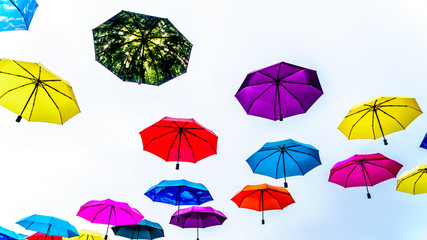 Fototapeta na wymiar Colorful Umbrellas floating in the air under cloudy sky