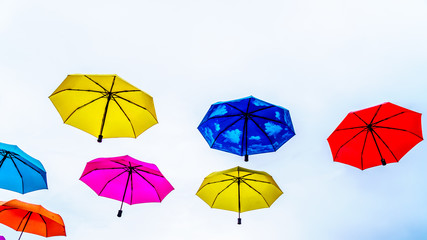 Colorful Umbrellas floating in the air under cloudy sky