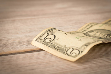Old 5 dollar bill on a wooden table. Close up. The concept of saving money.