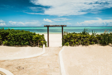 View of the arch, green bushes and the path to the turquoise water, Matemwe Beach, Zanzibar, Tanzania, Africa