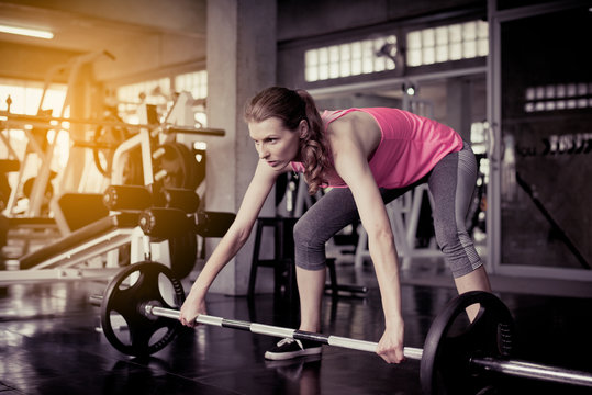 Sporty caucasian woman exercise with barbell,Female does the exercising at gym