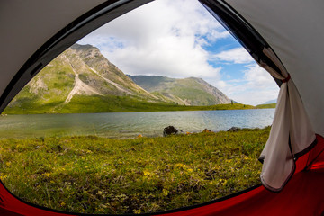 View from inside the tent out of the mountains and lake in the summer