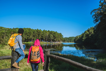 Couples travelers with backpack happy to relax on a holiday, travelers Pang-Ung park travel,Travel to visit nature landscape the beautiful at lake, at Mae-hong-son, in Thailand.