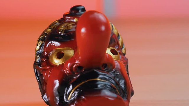 Old traditional Japanese Tengu red demon ceremonial mask on a table.