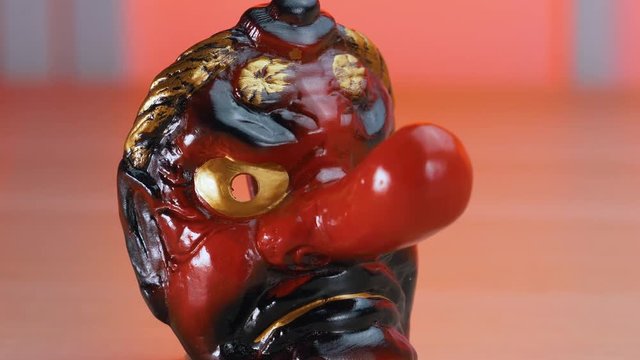 Old traditional Japanese Tengu red demon ceremonial mask on a table.