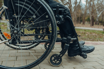 Close-up of male hand on wheel of wheelchair during walk in park