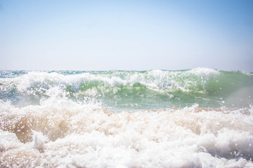 amazing green waves of the black sea foaming the yellow sand against the blue sky