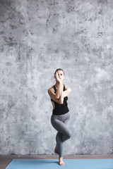 Full-length portrait of young beautiful woman doing yoga exercise indoors.