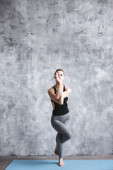 Fototapeta premium Full-length portrait of young beautiful woman doing yoga exercise indoors.