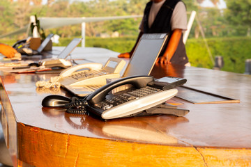 Telephone on hotel reception desk with customer check in at reception counter.