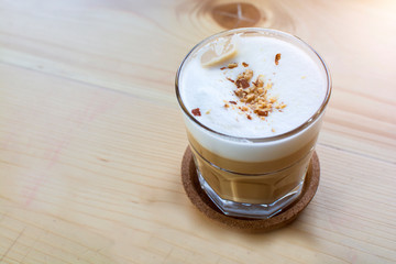 Glass of hot coffee drink with peanut on top on wooden table