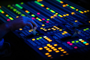 Close Up of a Video Control Switcher Board with brightlyColored Lights in a dark control room in a...