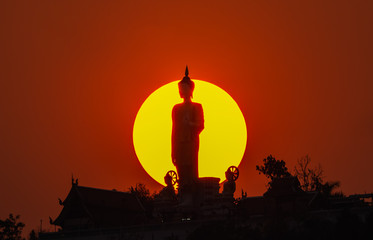 Silhouette of Buddha with sun shining from behind, Buddha statue over scenic sun sky background..