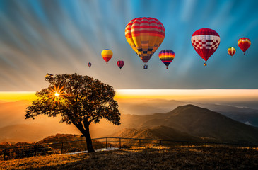 Colorful hot air balloons flying above high mountain at sunrise with beautiful sky background, Thailand.