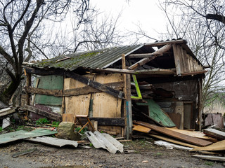 The destroyed wooden constructions. The deserted and plundered house. The broken wooden shed in the middle of garbage