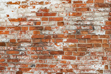 The texture of the old brick wall painted white with peeling paint