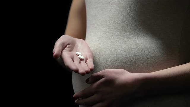 Pregnant woman holding pills, risk of birth defect after medicine, abortion drug