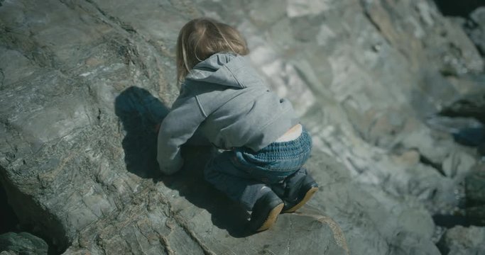 Little toddler climbing on a rock