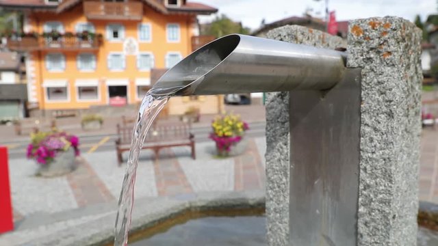 Water tube at the central square of Moena city in Italian Alps filmed in slow motion.