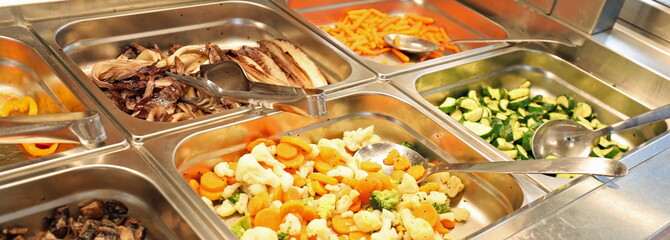 steel trays with plenty of vegetables cooked and raw in the cafe